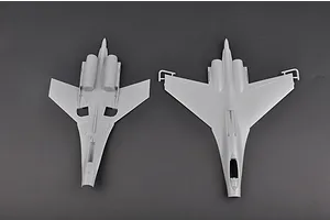 Top-down view of two unpainted grey plastic model aircraft fuselage and wing sections from a Trumpeter 1/72 Su-27 kit.