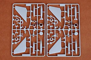 Two identical grey plastic model kit sprues labeled D, containing aircraft parts like wings, landing gear, and missiles on a brown surface.