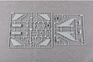 Two grey plastic model kit sprues containing aircraft parts, including wings and engine components, laid out on a textured grey surface.