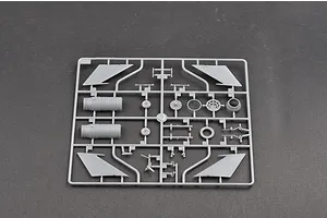 A grey plastic sprue containing various model aircraft parts, including engine components, landing gear, and wing sections, set against a dark grey background.