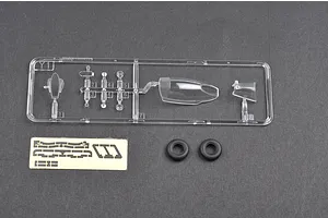 A clear plastic sprue containing canopy and small parts, a small sheet of masking tape, and two black rubber tires for a 1/48 scale model kit.