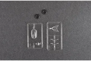 Clear plastic model kit sprues and two small black rubber rings on a dark grey background.
