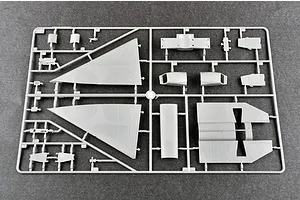 A grey plastic sprue containing various aircraft model parts, including large delta wings and fuselage sections, on a dark grey surface.