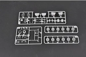 Three grey plastic model kit sprues containing various vehicle parts and wheels on a dark grey background.