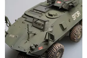 A high-angle close-up of a 1/35 scale model of a Canadian Grizzly AVGP armoured vehicle, painted in olive drab with SFOR markings.