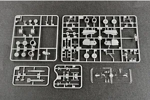 Four grey plastic model kit sprues and one clear plastic sprue containing aircraft parts laid out on a dark surface.