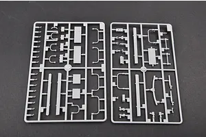 Two grey plastic model kit sprues containing various small vehicle parts laid out on a dark surface.