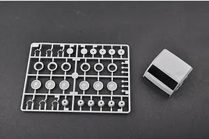A grey plastic sprue containing various wheel and hub parts alongside a separate molded truck cab piece for a 1/35 scale model kit.