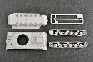 Top-down view of unpainted grey plastic model tank parts including the hull, turret base, and track assemblies on a dark grey background.