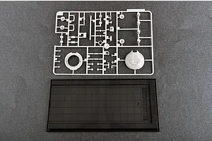 A plastic model kit sprue containing tank parts and a black display base on a grey background.