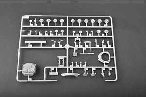 A grey plastic sprue containing various unpainted model tank parts, including wheels and turret components, against a dark grey background.