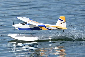 FMS Super EZ V3 RC seaplane taxiing on water, showing its white, blue, and orange livery and floats.