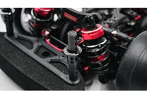 Close-up of a black adjustable aluminium body mount installed on an RC car chassis, featuring the Yeah Racing logo on the collar.