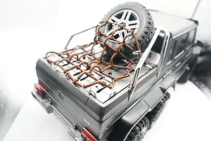 A GPM Racing stainless steel tray cover with a brown cargo net installed on the rear bed of a grey Traxxas TRX-6 RC Mercedes-Benz G 63 AMG 6x6.
