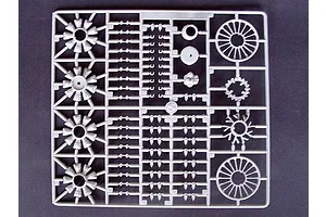 A grey plastic sprue from a model kit containing various engine parts and circular components.
