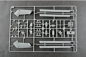 A grey plastic sprue containing various model helicopter parts, including rotor blades and fuselage sections, on a dark grey background.