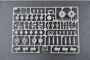 A grey plastic sprue containing various model tank parts, including road wheels, sprockets, and suspension components, viewed from above.