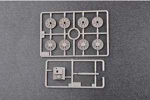 Two grey plastic model kit sprues containing tank road wheels and a small turret component on a dark grey background.