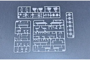 Three grey plastic model kit sprues containing various vehicle parts laid out on a dark surface.