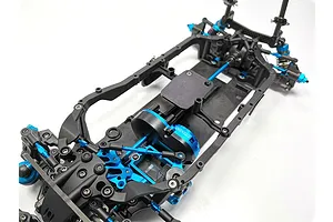 Top-down view of a Tamiya TB-05R RC touring car chassis featuring a black frame with blue anodized aluminum components.