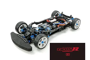 A high-angle studio shot of a Tamiya TB-05R 1/10 scale RC touring car chassis kit, featuring blue anodized aluminum parts and black carbon fiber components.