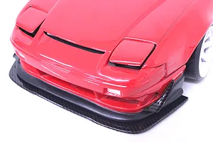 Close-up of a red RC car front bumper fitted with a carbon-style under panel splitter.