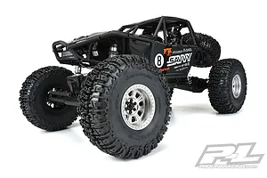 A black RC rock crawler vehicle equipped with large, aggressive Pro-Line Trencher tyres on silver beadlock wheels, shown against a white background.