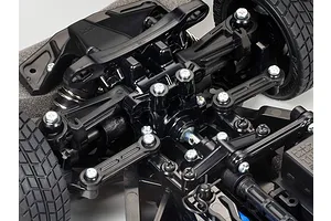 Close-up of the front suspension and steering assembly of a Tamiya TT-02 RC car chassis, showing black plastic components and metal screws.