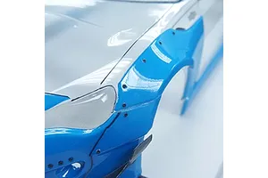 Close-up of a blue RC car fender flare attached to a white body shell with small black micro screws.