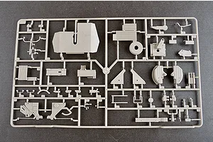 A grey plastic sprue containing various unpainted model kit parts for a military vehicle, laid out on a dark grey surface.