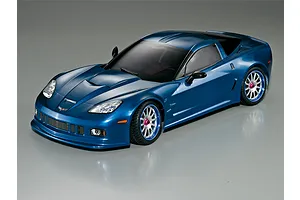 A 1/10 scale metallic blue Corvette GT2 RC car body shell mounted on a chassis with silver multi-spoke wheels and pink wheel nuts.
