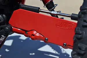 A close-up view of a red RPM mud guard installed on the rear suspension arm of an ARRMA RC vehicle.
