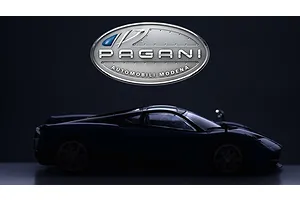 A dark silhouette of a Pagani Huayra model car positioned below the silver Pagani Automobili logo against a dark background.