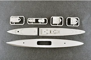 Top-down view of unpainted plastic model ship parts including the hull, deck sections, and small superstructure components on a grey surface.