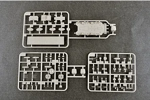 Three grey plastic model kit sprues for a 1/700 scale HMS Belfast ship model, showing various small parts and a deck section on a dark grey surface.