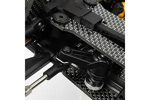 Close-up of a black aluminium steering brace installed on an RC car chassis with carbon fibre components.