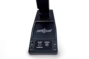 Close-up of the base of a black Team Powers LED pit light, showing the control panel with On/Off, Brightness, and Light Mode buttons and tool storage holes.