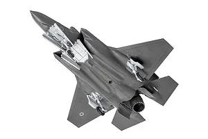 A high-angle view of an assembled and unpainted grey plastic model of an F-35B Lightning II fighter jet, showing the underside details.