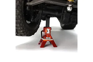 A red scale model jack stand supporting the axle of an RC vehicle against a white background.