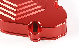 Close-up of a red anodized aluminium transmission case for an RC car, showing the machined stepped design and mounting holes.
