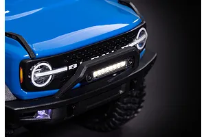 Close-up of a blue RC Ford Bronco front end featuring an illuminated LED light bar mounted on the front bumper.