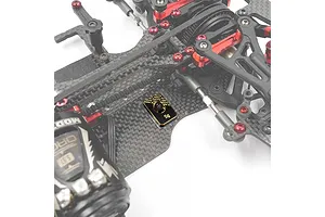 A 5g Yeah Racing brass balancing weight installed on a carbon fiber RC car chassis.