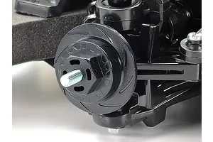 Close-up of a black plastic RC car wheel hub and suspension assembly on a Tamiya TT-02 chassis.