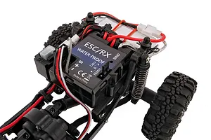 Close-up of the internal electronics and chassis of an Element RC Enduro24 rock crawler, showing the ESC/RX unit, wiring, and suspension.
