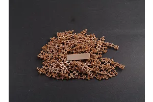 A pile of small brown plastic model tank track links on a dark grey surface.