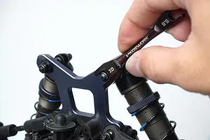 A hand using a black Koswork 5.5mm and 7mm turnbuckle wrench on an RC car suspension component.