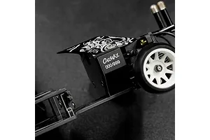 Close-up of an Onisiki Kodama RC drift car chassis showing the numbered serial plate and decorative wave pattern on the black frame.
