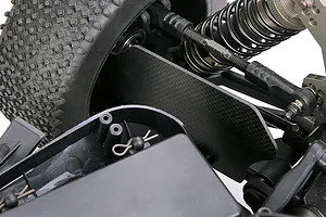 Close-up of a carbon fibre suspension arm guard installed on an RC vehicle chassis, showing the weave pattern and surrounding suspension components.