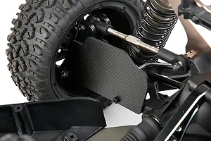 A close-up view of a carbon fibre rear suspension arm guard installed on an RC car, showing the weave pattern and mounting hardware.