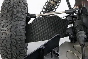 Close-up of a carbon fibre rear suspension arm guard installed on an RC vehicle, showing the weave pattern and mounting position.